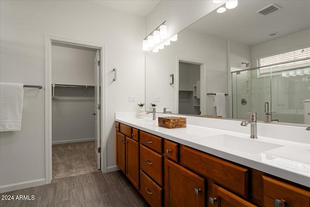 bathroom with wood-type flooring, a shower with door, and vanity