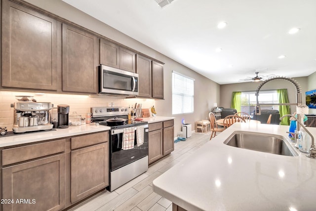 kitchen featuring decorative backsplash, sink, ceiling fan, and stainless steel appliances