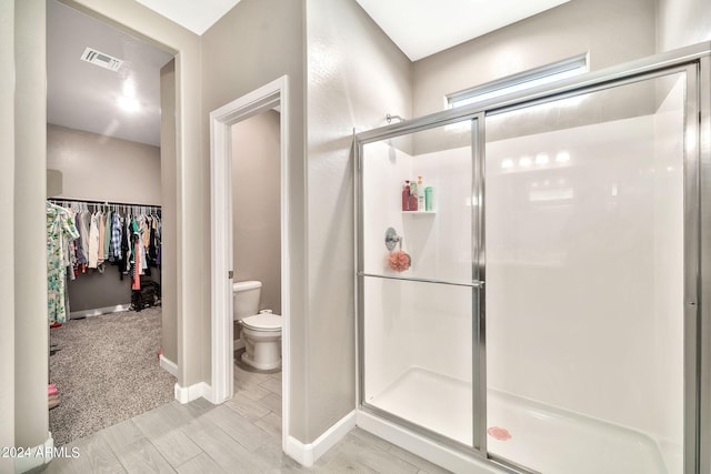 bathroom with wood-type flooring, toilet, and an enclosed shower