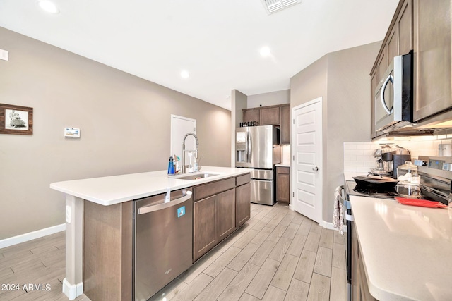 kitchen featuring light wood-type flooring, a kitchen island with sink, sink, and stainless steel appliances