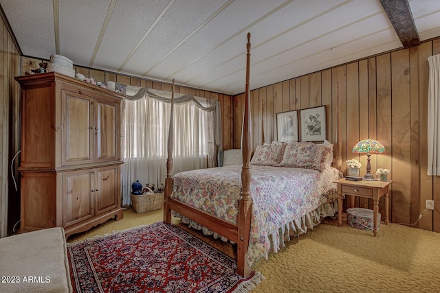 bedroom with a textured ceiling, carpet floors, and wooden walls