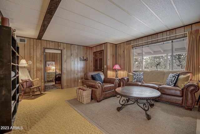 living room with a textured ceiling, carpet, and beamed ceiling