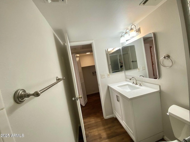 bathroom featuring toilet, wood finished floors, and vanity