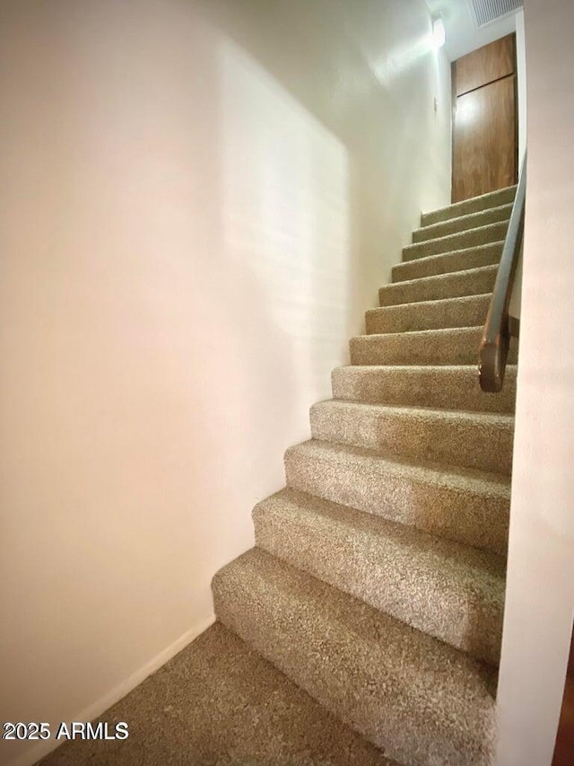 staircase featuring baseboards and carpet