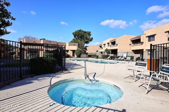 community pool featuring a community hot tub, fence, a patio, and a residential view