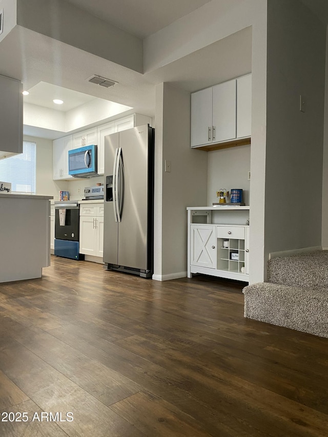 kitchen featuring dark wood-type flooring, white cabinetry, stainless steel refrigerator with ice dispenser, a raised ceiling, and electric range oven