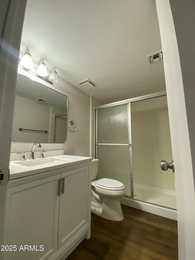 bathroom featuring a shower stall, vanity, visible vents, toilet, and wood finished floors
