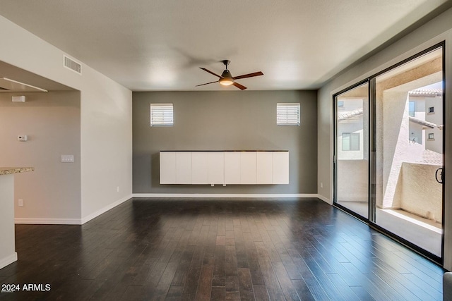 empty room featuring dark wood-type flooring, ceiling fan, and a healthy amount of sunlight