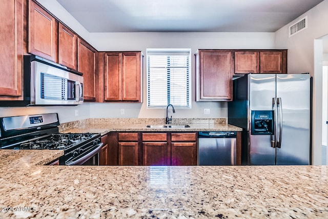 kitchen with sink, light stone countertops, and stainless steel appliances