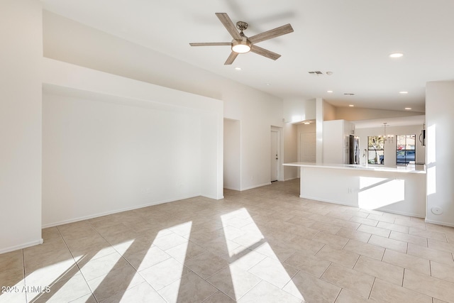 unfurnished living room featuring ceiling fan with notable chandelier, vaulted ceiling, and light tile patterned floors