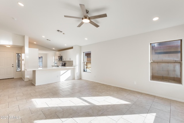 kitchen with a kitchen bar, vaulted ceiling, light tile patterned floors, ceiling fan, and white cabinets