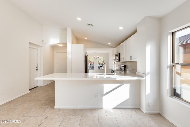 kitchen with sink, white cabinetry, vaulted ceiling, appliances with stainless steel finishes, and kitchen peninsula