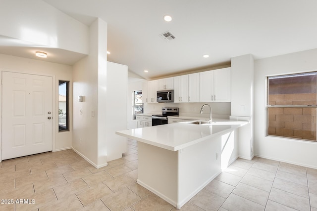 kitchen featuring sink, vaulted ceiling, kitchen peninsula, stainless steel appliances, and white cabinets