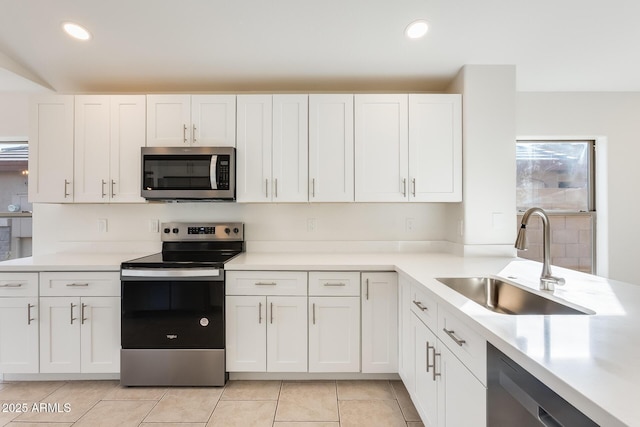 kitchen featuring stainless steel appliances, white cabinetry, sink, and light tile patterned flooring