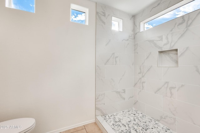 bathroom with a tile shower, tile patterned flooring, and toilet