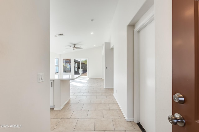 corridor with light tile patterned flooring and lofted ceiling