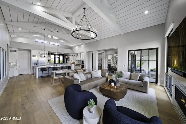 living room featuring beam ceiling, a chandelier, high vaulted ceiling, and light hardwood / wood-style flooring