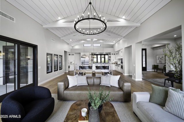 living room featuring wood-type flooring, a chandelier, and high vaulted ceiling