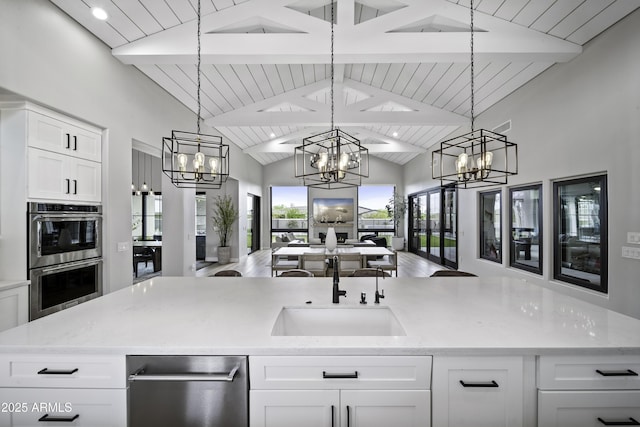 kitchen featuring pendant lighting, sink, white cabinetry, an inviting chandelier, and stainless steel double oven