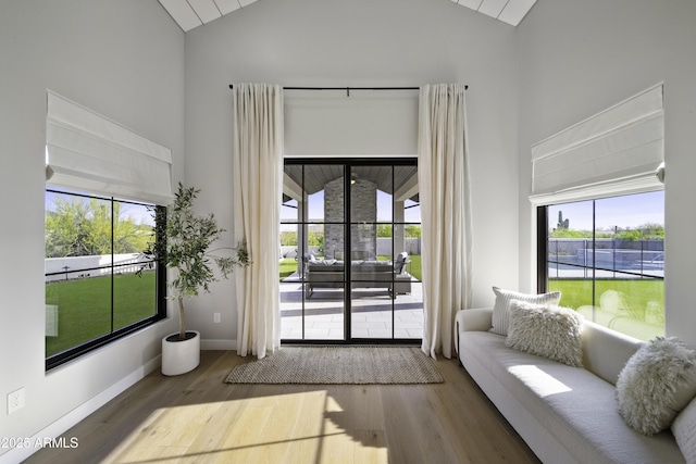 doorway to outside featuring hardwood / wood-style flooring, vaulted ceiling, and a wealth of natural light