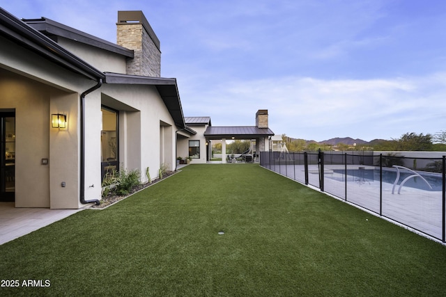 view of yard featuring a fenced in pool, pool water feature, a mountain view, and a patio area