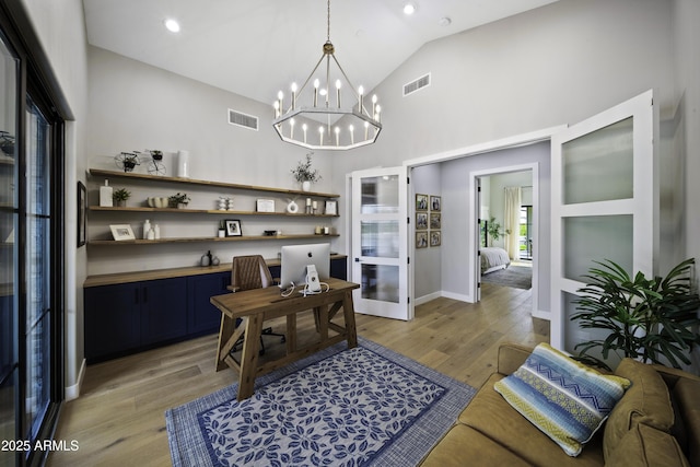 office featuring a notable chandelier, high vaulted ceiling, and light wood-type flooring