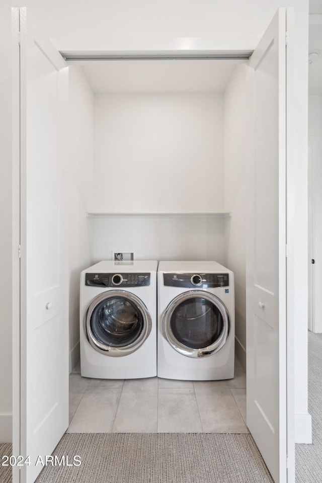 clothes washing area with light tile patterned floors and washing machine and clothes dryer