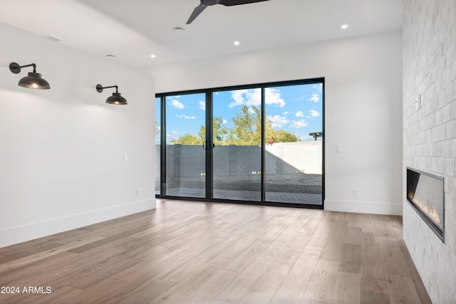 unfurnished living room with a tile fireplace, light hardwood / wood-style flooring, and ceiling fan