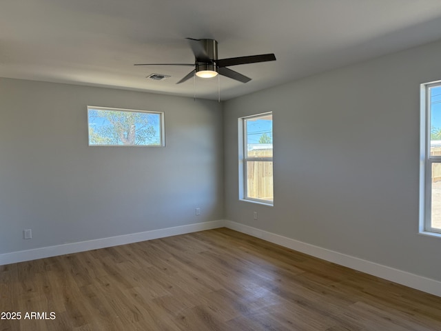 unfurnished room featuring baseboards, a ceiling fan, wood finished floors, and visible vents