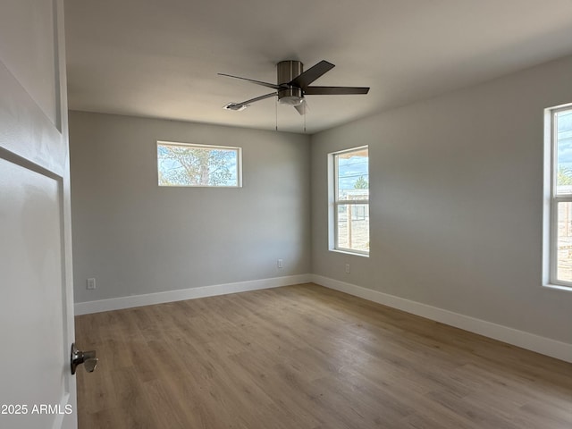 empty room with a ceiling fan, wood finished floors, and a healthy amount of sunlight
