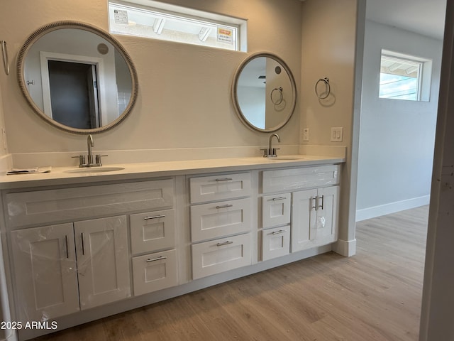 full bath featuring double vanity, a sink, and wood finished floors