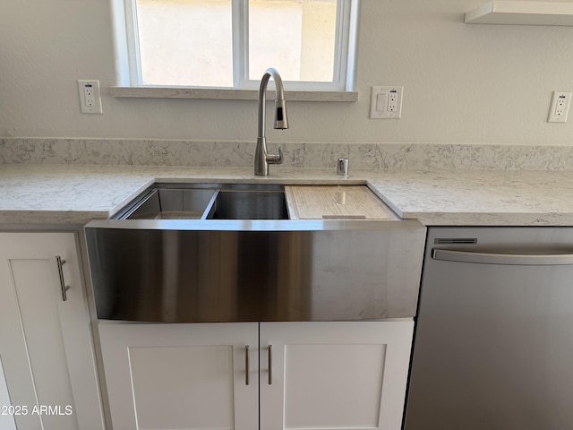 kitchen featuring white cabinets, a sink, and dishwasher