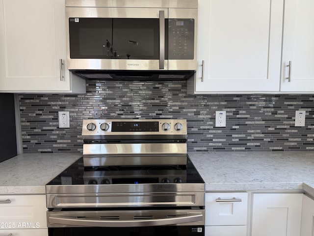 kitchen featuring backsplash, stainless steel appliances, light stone counters, and white cabinetry