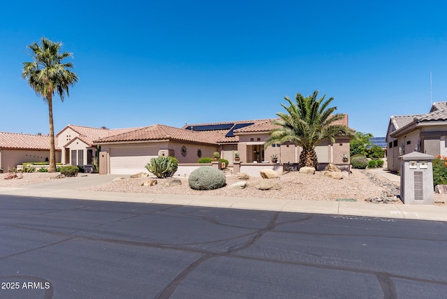 20394 N Coronado Way, Surprise, AZ 85374 - mediterranean / spanish-style home featuring stucco siding, roof mounted solar panels, a tiled roof, an attached garage, and concrete driveway
