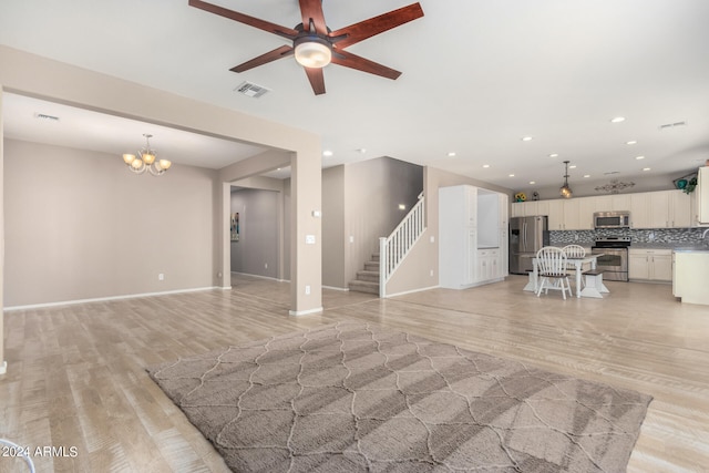 living room featuring ceiling fan with notable chandelier and light hardwood / wood-style floors