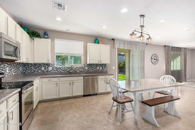 kitchen featuring a chandelier, backsplash, sink, stainless steel appliances, and hanging light fixtures