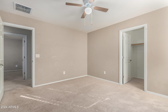 unfurnished bedroom featuring ceiling fan, light colored carpet, a closet, and a spacious closet