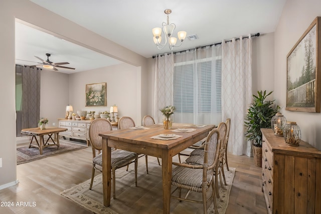 dining area with ceiling fan with notable chandelier and hardwood / wood-style flooring