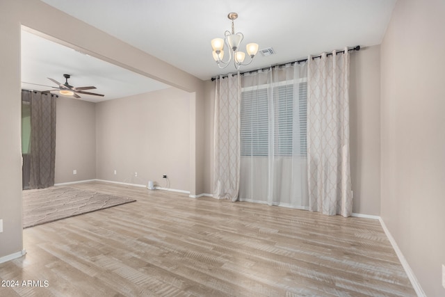 spare room with ceiling fan with notable chandelier and light wood-type flooring