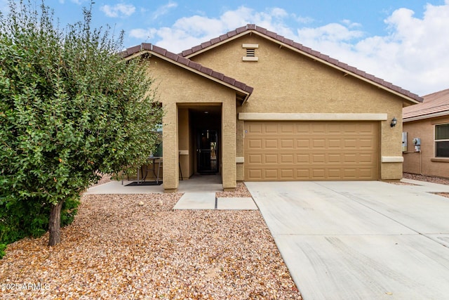 view of front of property with a tile roof, driveway, an attached garage, and stucco siding