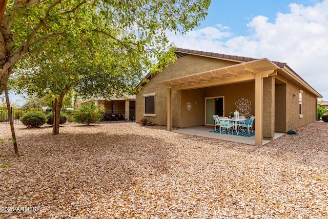 rear view of house with a patio area, fence, and stucco siding