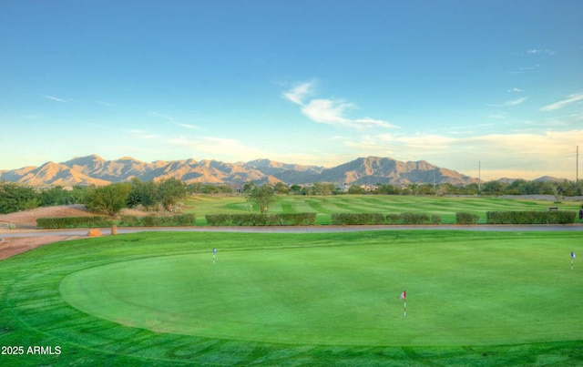 view of community with view of golf course, a mountain view, and a lawn