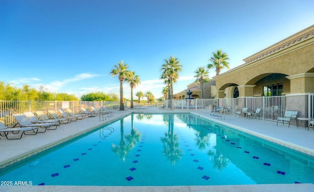 pool with a patio area and fence