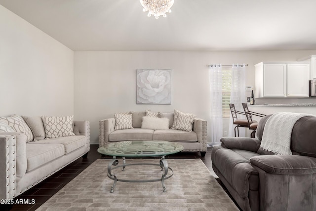 living area with baseboards, dark wood-type flooring, and an inviting chandelier