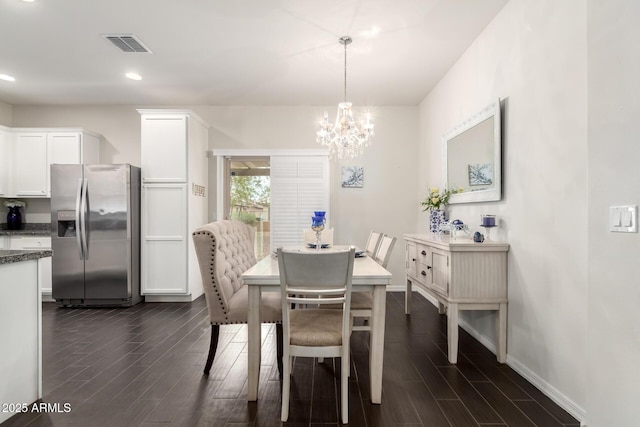 dining area featuring dark wood-style flooring, visible vents, a notable chandelier, and baseboards