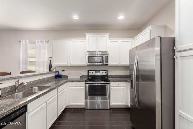 kitchen with recessed lighting, stainless steel appliances, a sink, white cabinets, and dark stone countertops