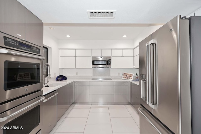 kitchen featuring gray cabinetry, sink, stainless steel appliances, light tile patterned floors, and white cabinets