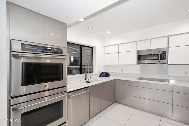 kitchen featuring gray cabinets, sink, light tile patterned floors, and stainless steel appliances