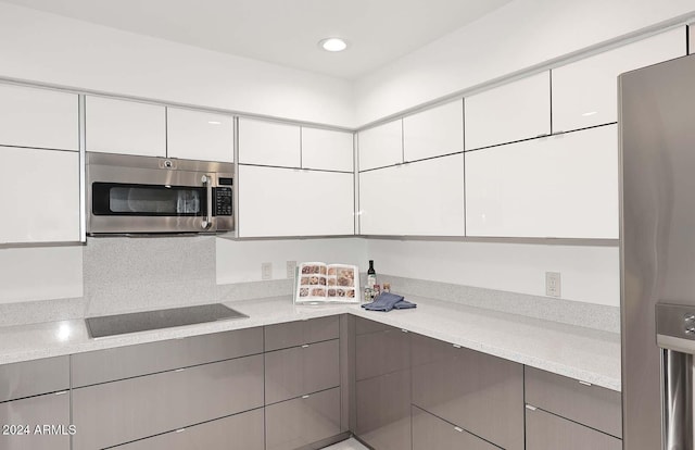 kitchen featuring white cabinetry, light stone countertops, and appliances with stainless steel finishes