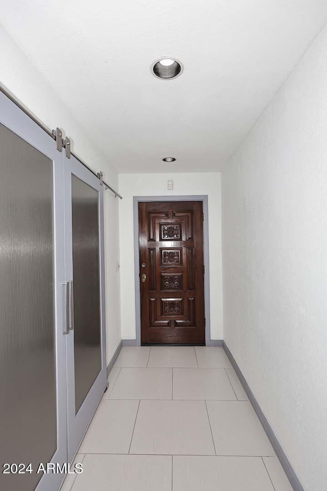 hall featuring light tile patterned floors and a barn door